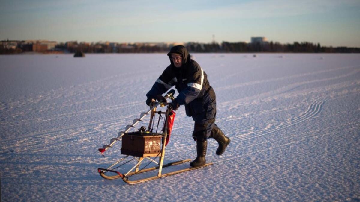 A man going ice-fishing slides on a vintage sled carrying a powerdrill and his fishing gear on the frozen Bothnia Sea, on December 28, 2016 in Vaasa, Western Finland. (OLIVIER MORIN/AFP)