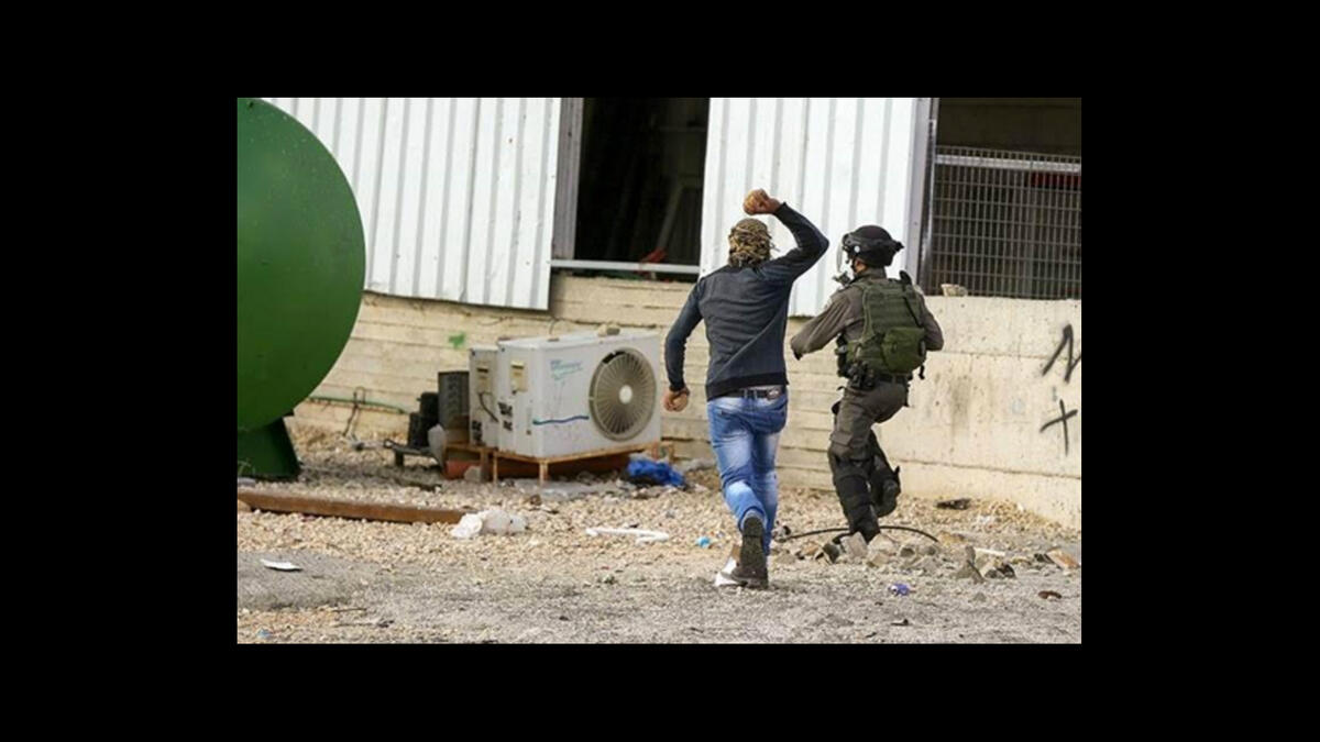 palestinian chases israeli soldier with stone