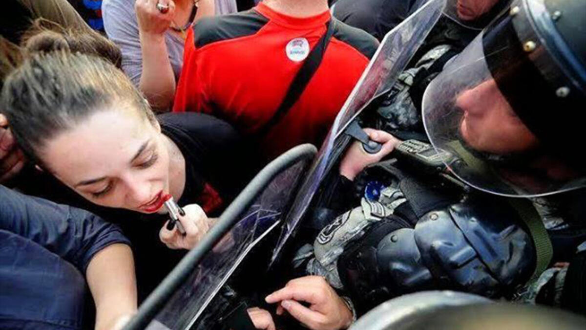 applying lipstick using riot police shield 'mirror'