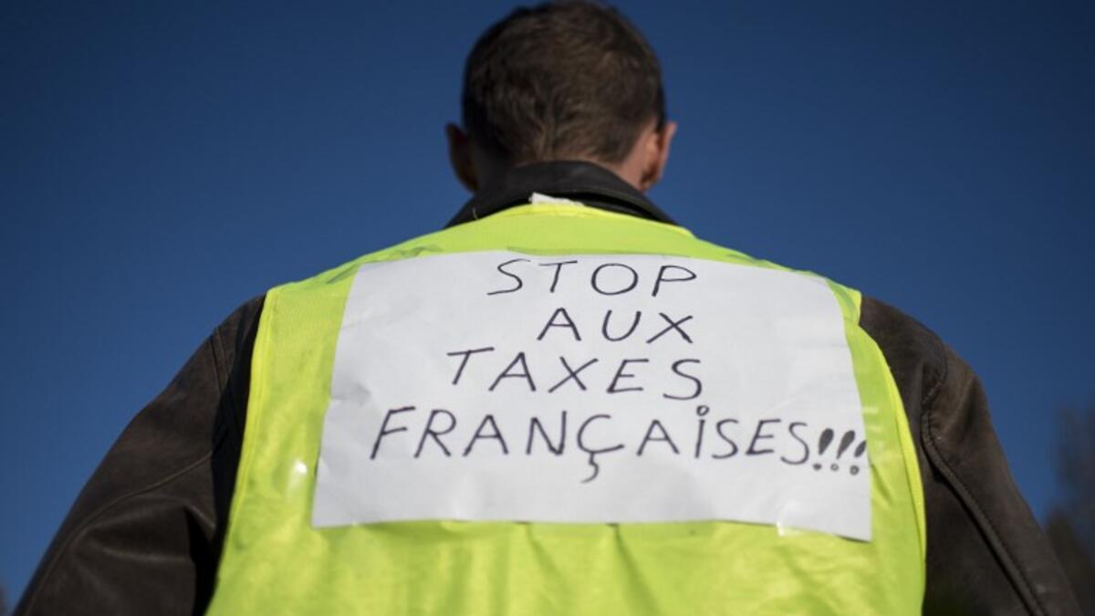 A man wears a yellow vest with the inscription "Stop to French taxes" while protestors slow down traffic on a road in Saint-Herblain, near Nantes, western France.
SEBASTIEN SALOM GOMIS / AFP