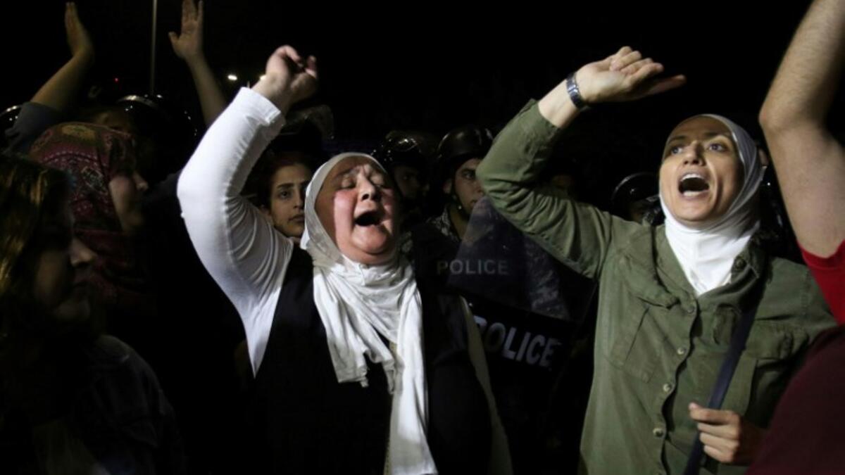 Protesters raise their fists near riot police officers during a demonstration outside the prime minister's office in the capital Amman late on June 3, 2018. 
Khalil MAZRAAWI / AFP
