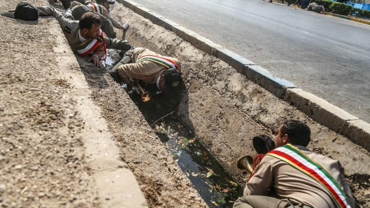 This picture taken on September 22, 2018 in the southwestern Iranian city of Ahvaz shows Iranian soldiers taking cover in a rain gutter off a street at the scene of an attack on a military parade that was marking the anniversary of the outbreak of its devastating 1980-1988 war with Saddam Hussein's Iraq.(MORTEZA JABERIAN / ISNA / AFP)