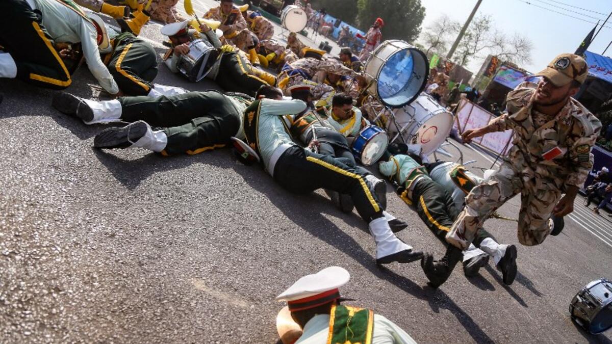 This picture taken on September 22, 2018 in the southwestern Iranian city of Ahvaz shows a soldier running past injured comrades lying on the ground at the scene of an attack on a military parade. (MORTEZA JABERIAN / ISNA / AFP)