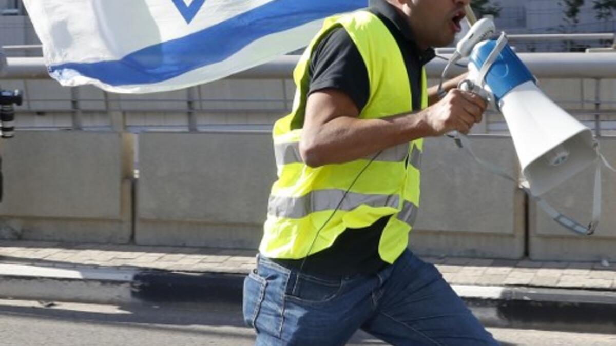 An Israeli protester wearing a yellow vest and carrying a national flag use a loudspeaker to shout slogans during demonstrations against the rising cost of living on December 14, 2018.
JACK GUEZ / AFP