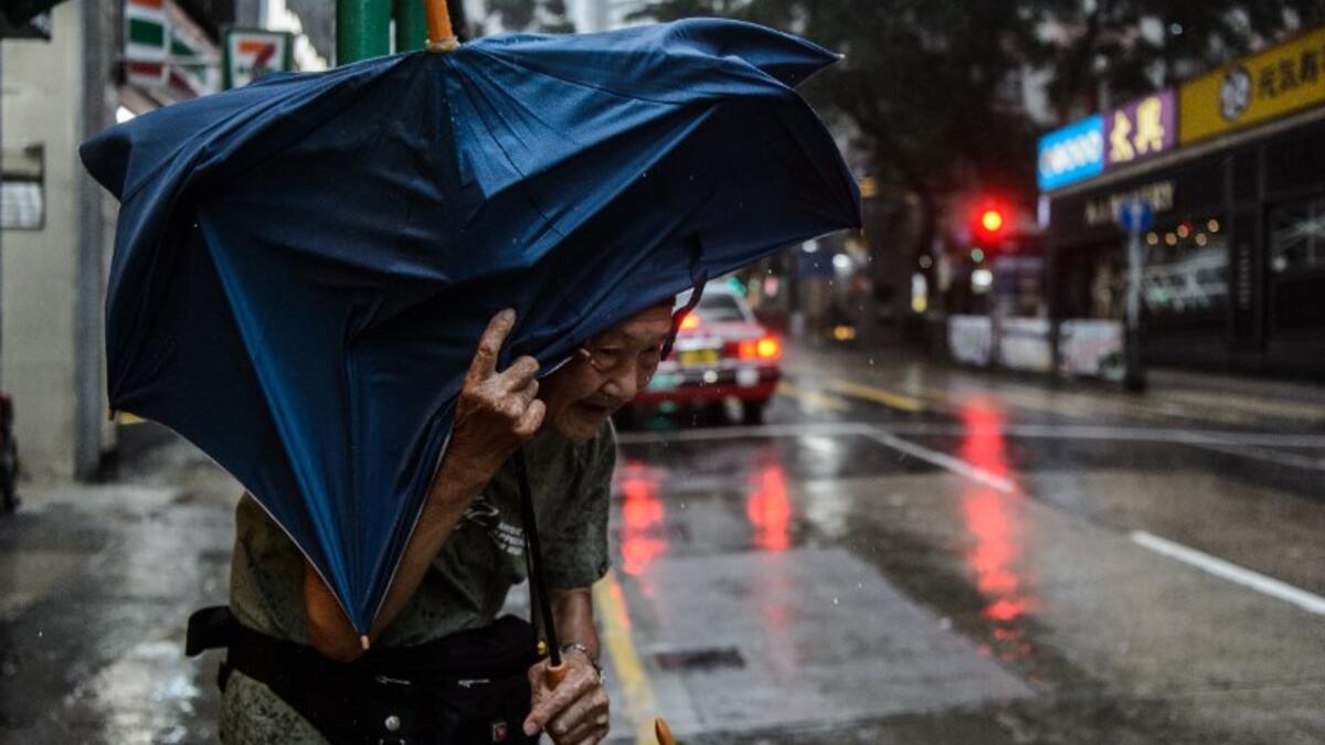 An elderly man waits for a taxi while holding his umbrella as super Typhoon Mangkhut edges closer to Hong Kong on September 16, 2018. 
Anthony WALLACE / AFP