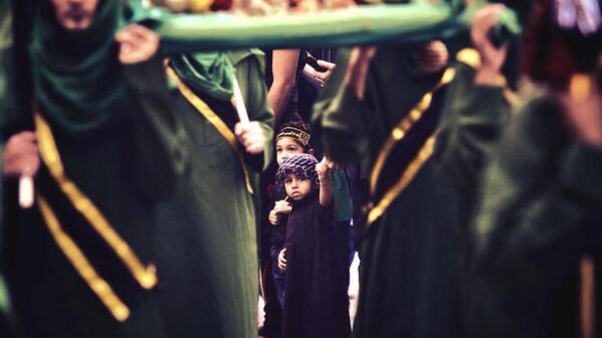 Shiite Muslim boy holds his father's hand during a ceremony (Twitter)