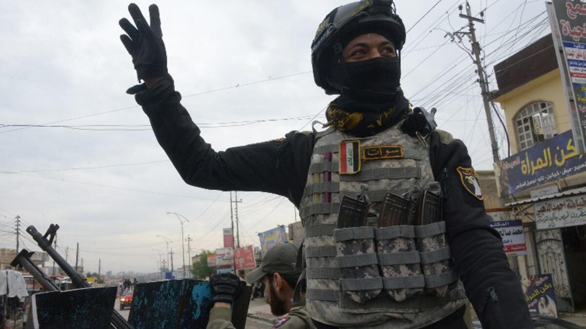 A member of the Iraqi security forces salutes onlookers as he parades in the streets of the Iraqi city of Mosul, during celebrations marking the first anniversary of the country's victory over the Islamic State (IS) group. 
Zaid AL-OBEIDI / AFP