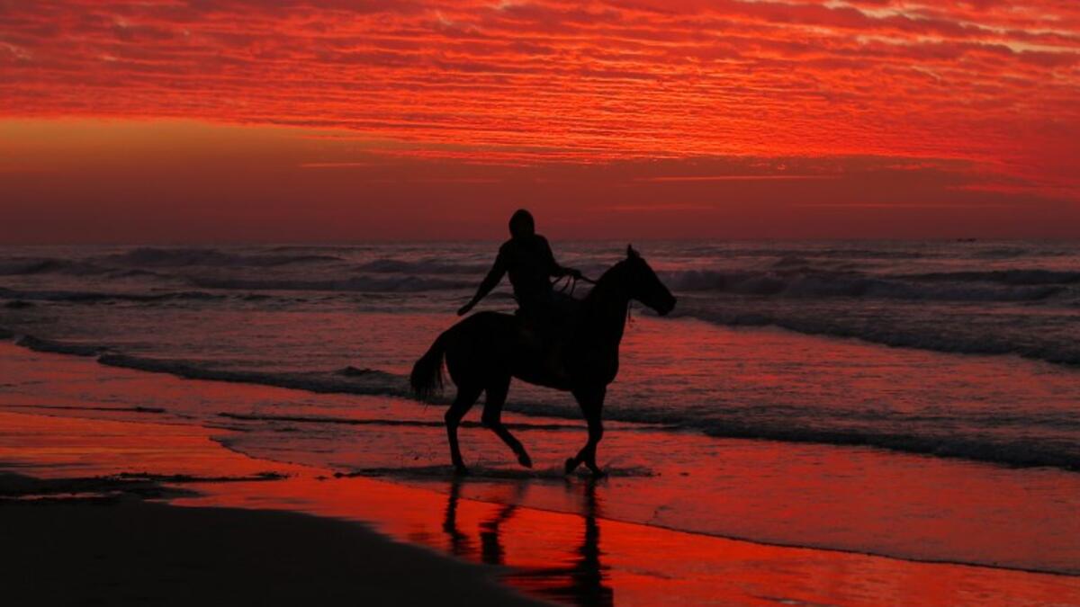 A Palestinian horseman rides on the beach at sunset, west of in Gaza city on December 31, 2018. 
MAHMUD HAMS / AFP