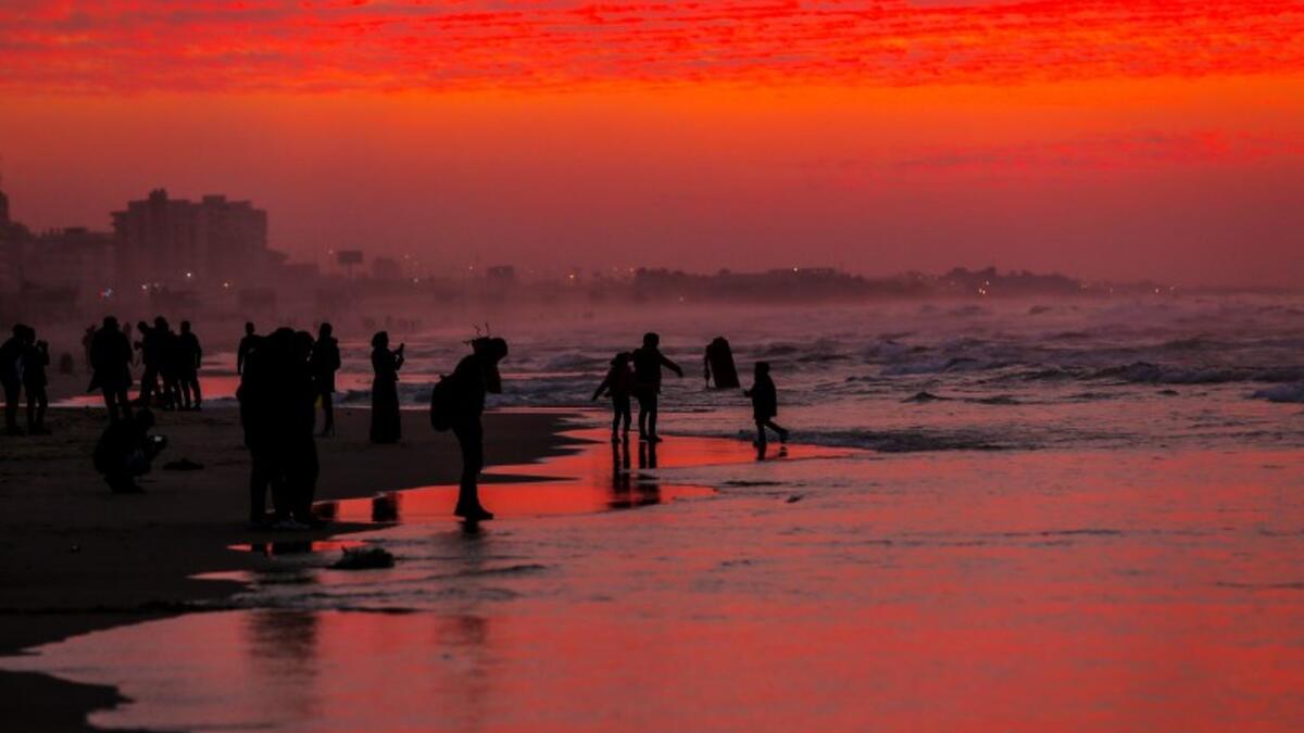 Palestinian people walk on the beach at sunset west of in Gaza city on December 31, 2018. 
MAHMUD HAMS / AFP