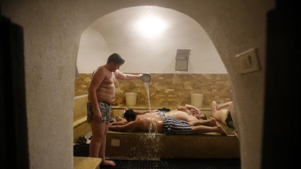 A man pours water on others lying on their bellies inside the steam room of the first traditional Turkish bath (Hammam) opening in the occupied Palestinian West Bank city of Hebron on March 11, 2019. 
HAZEM BADER / AFP