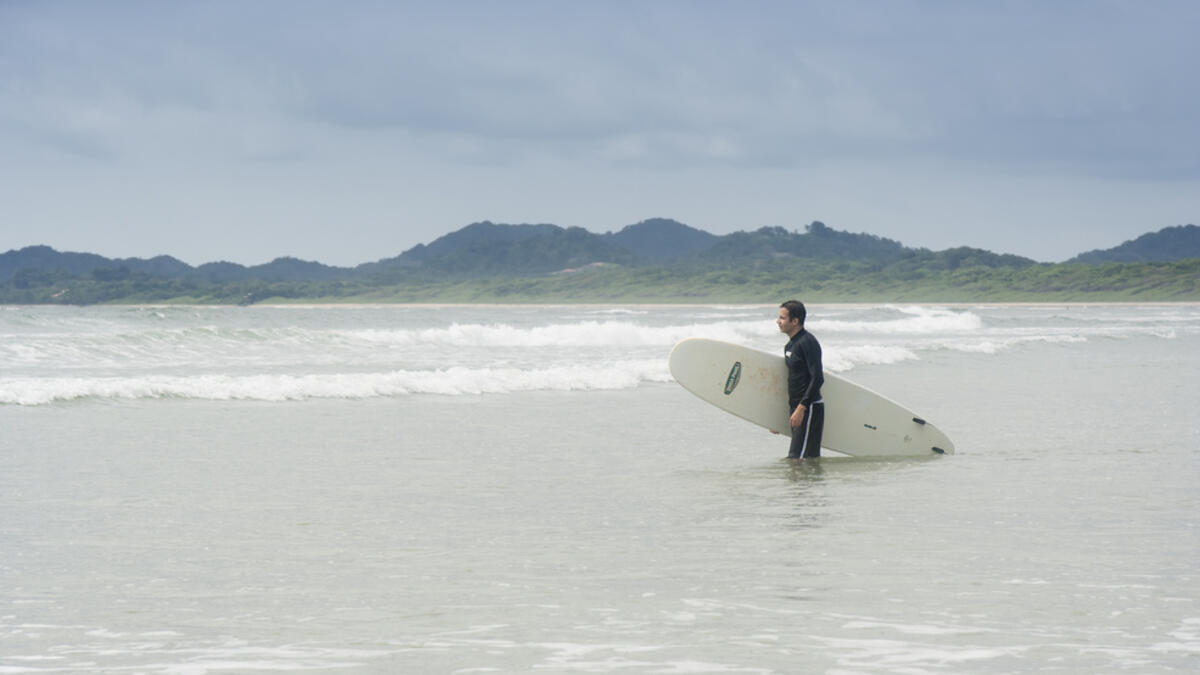 Young man going to surf in Tamarindo, Costa Rica. Tamarindo is located on the Northern Pacific Coast and a leading surfer hotspot. (Shutterstock)