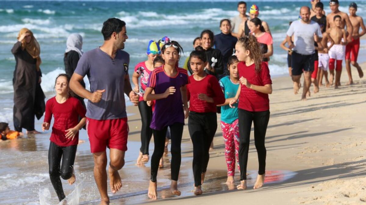 Young Palestinian members of a swimming club, run on the beach during a training session in Beit Lahia in the northern Gaza Strip. (SAID KHATIB / AFP)