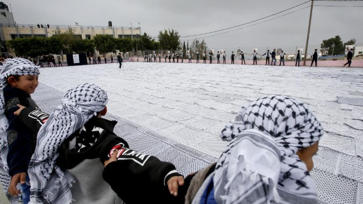 Palestinian students of the Southern Education Direction surround the largest Keffiyeh. (HAZEM BADER / AFP)