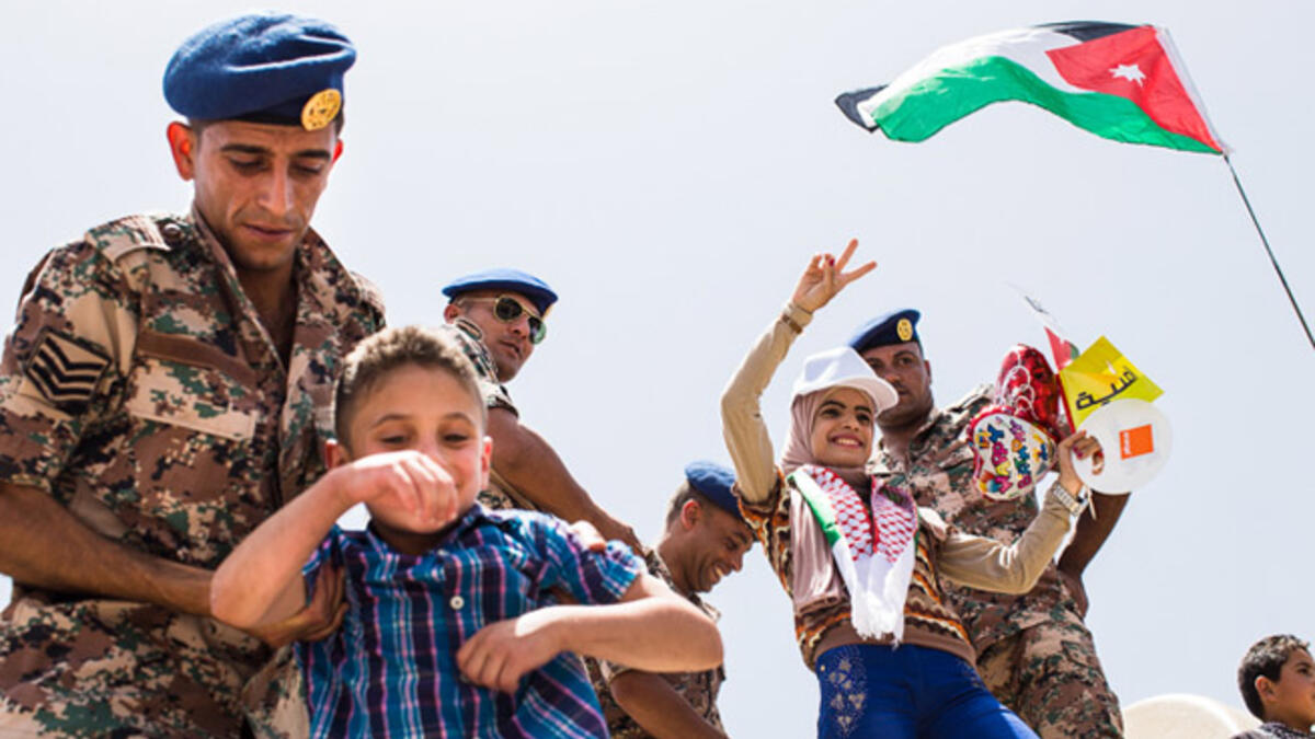 A Jordanian soldier helps a boy get on top of a tank for a photo, while another woman poses with soldiers. Large official and impromptu celebrations were held in Amman to mark the centennial of the Great Arab Revolt on June 3, 2016.