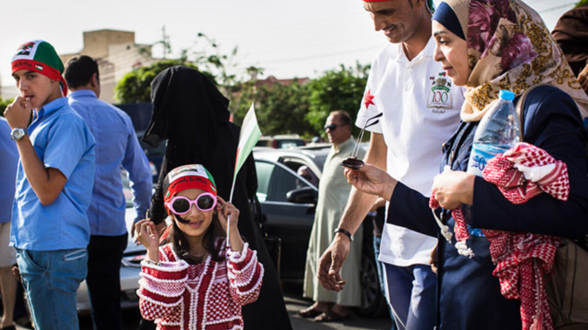 A young Jordanian girl, wearing a dress made out of a traditional kuffiyeh, tries on her pink sunglasses as she and her parents head to the festival.
