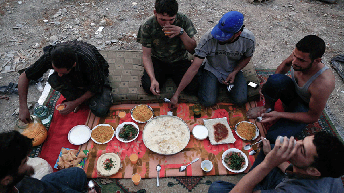 Fighters from the Syrian army gather for a simple Iftar dinner. Inflation and extremely high food prices have made it costly for many people to afford Iftar meals. Often, families cannot afford dates and milk to break their fast. Many also live without the traditional sweets, due to the skyrocketing prices for sugar.