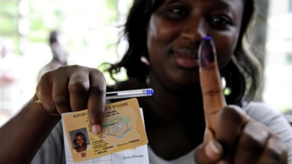 A woman shows documents and a ink-stained finger after voting at a polling station in Abidjan, during the second round of Presidential elections.