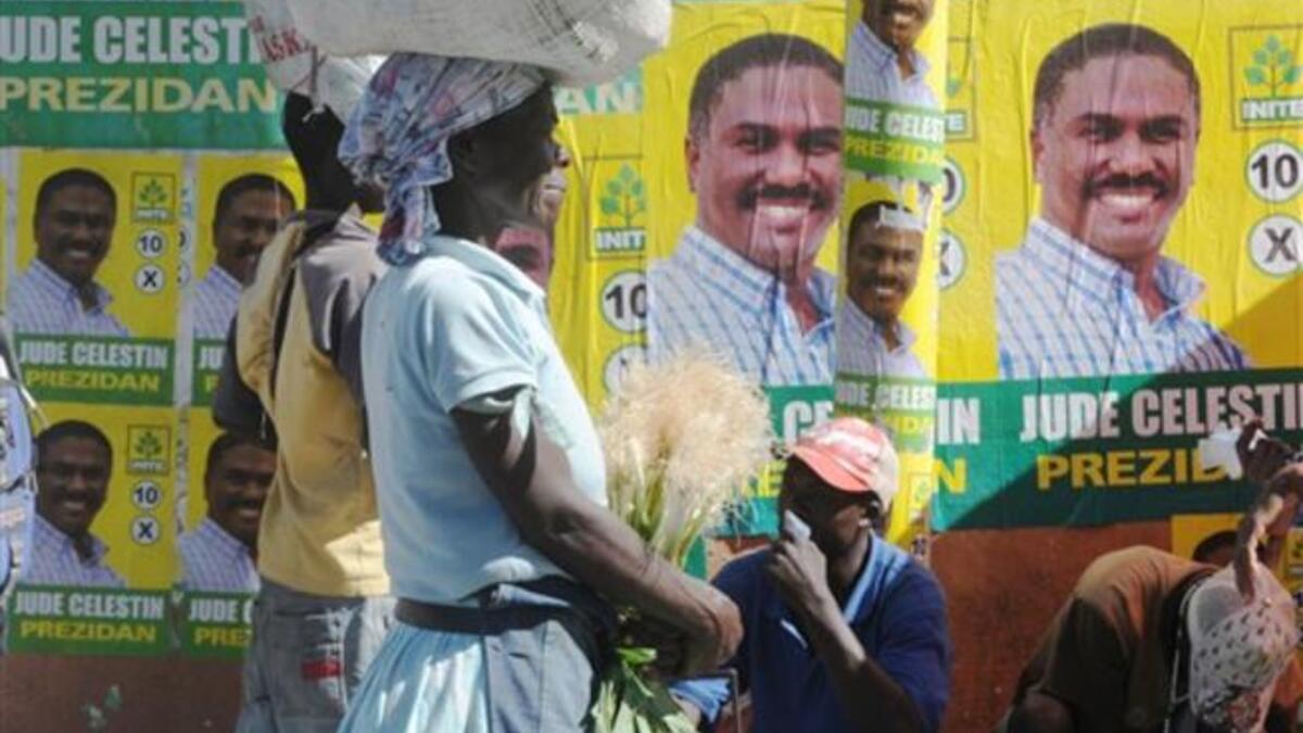 A Haitian woman passes in front of presidential candidate Jude Celestin posters in Petion-Ville. Deadly violence rocked the run-up to Haiti elections and protests simmered over the handling of a raging cholera outbreak, feeding fears Tuesday that the nation could slip toward broader unrest