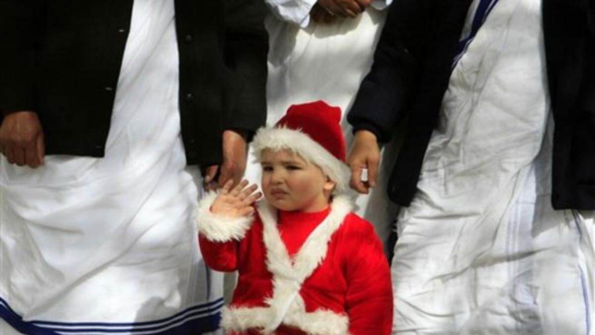 A Palestinian Christian boy wearing a Santa Claus costume waves during a ceremony ahead of Christmas attended by the head of the Roman Catholic Church in the Holy Land, the Latin Patriarch of Jerusalem Fuad Twal, outside the Latin Catholic Church in Gaza City.