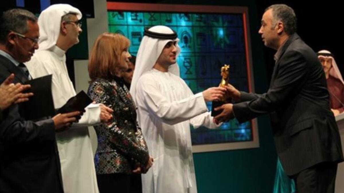 Sheikh Said bin Mohammed bin Rashed al-Maktoum (C) hands Lebanese film director George Hashem the best film Muhr Award for his movie Stray Bullet.
