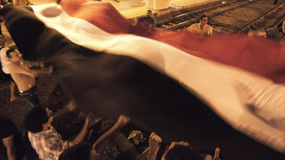 Opponents of the Egyptian president wave a giant national flag outside the presidential palace (AFP)