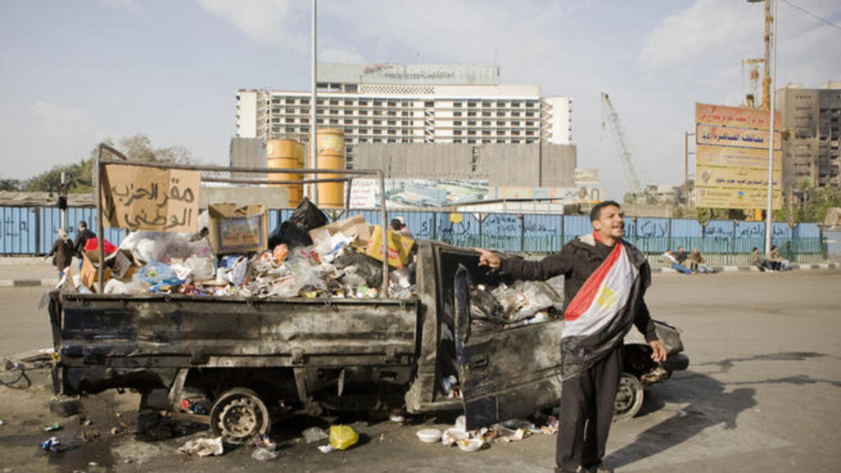 A burnt car filled with garbage sports a sign reading, "National Party Headquarters".