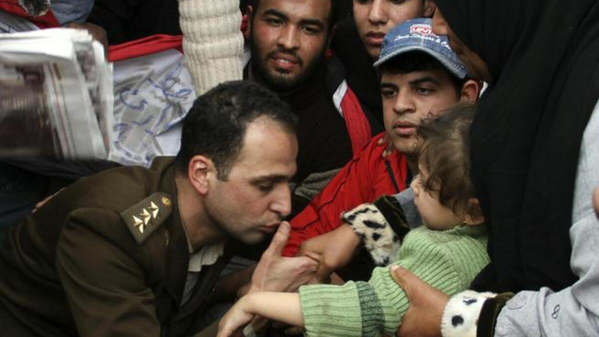 An Egyptian officer shows his position of solidarity with his people by a kiss to a child in the arms of its mother.