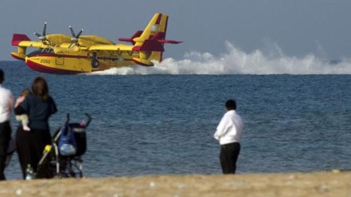 A firefighting airplane prepares to replenish water from the Mediterranean sea near the city of Haifa as the deadly fire which has swept a forest in northern Israel has almost come to an end following a four-day battle aided by aircraft from the around the world.