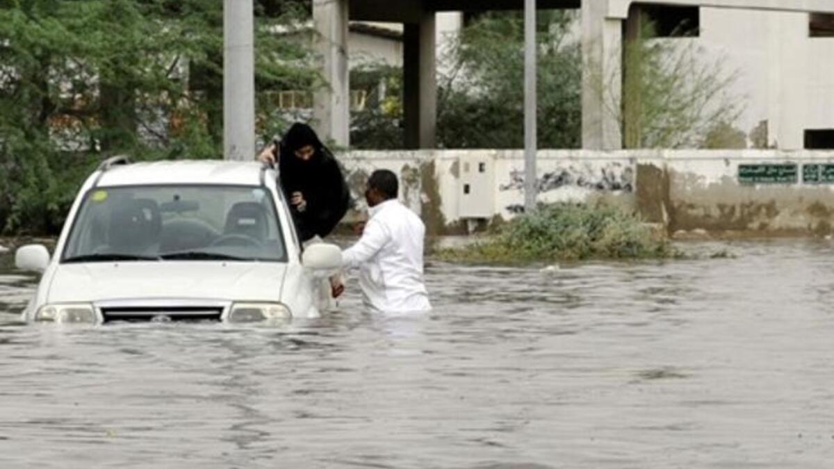 A Saudi man and a woman leave their car after it got stuck in a flooded street following heavy rain in the Red Sea port city of Jeddah.