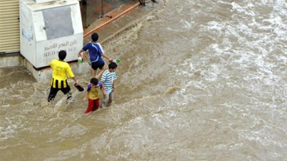 Saudi children walk through a flooded street following heavy rain.