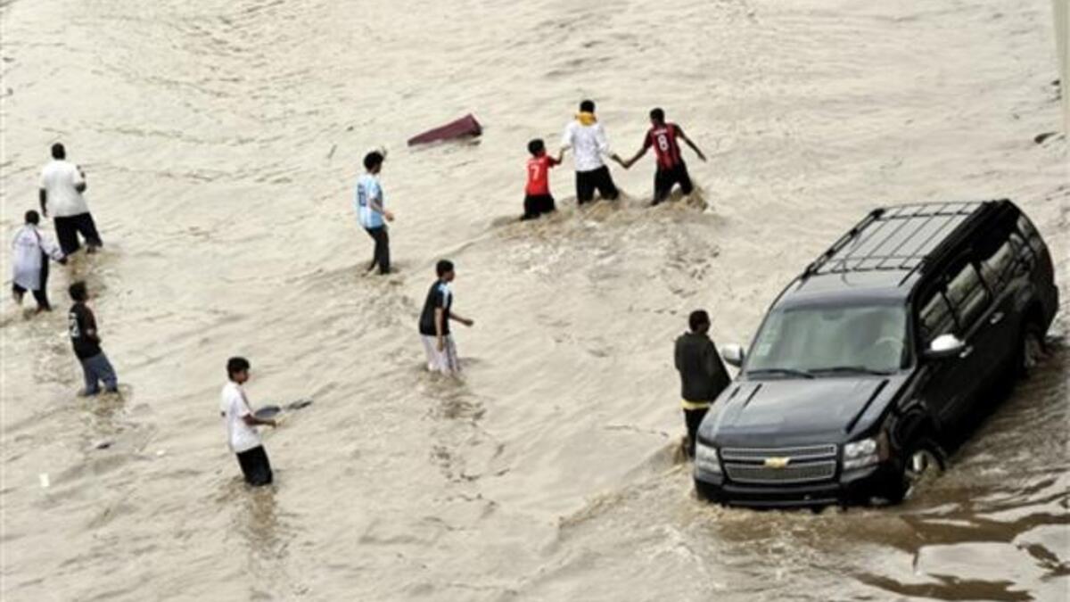Enjoying the disaster is easier than sadness, as Saudis are walking through the flooded street.