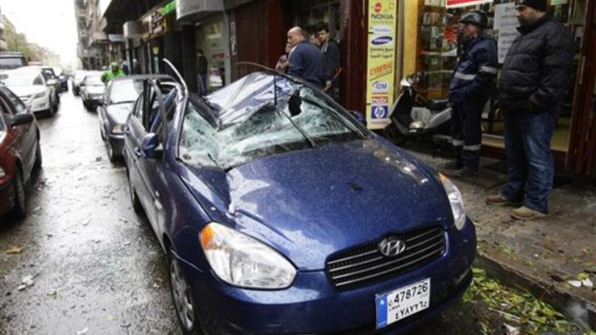 A car is damaged by a satellite dish which fell off the roof of a building in Beirut.