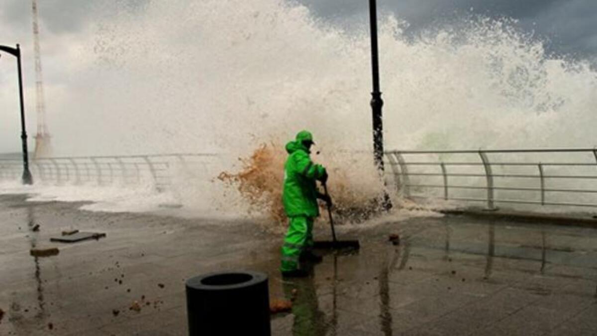 A municipality worker clears the mud as high waves rip off paving stones on Beirut's Mediterranean promenade.