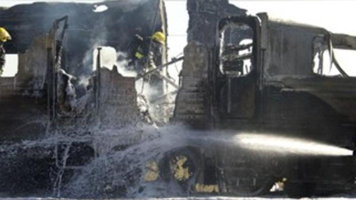 Israeli fire fighters spray water to extinguish the flames of a burning train coach.