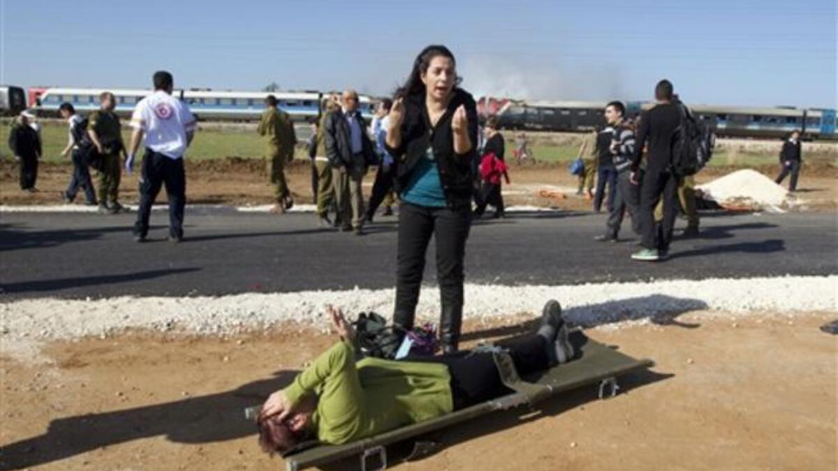 An Israeli woman reacts as she stands next to a wounded woman waiting to be evacuated on a stretcher at the scene of a train fire.