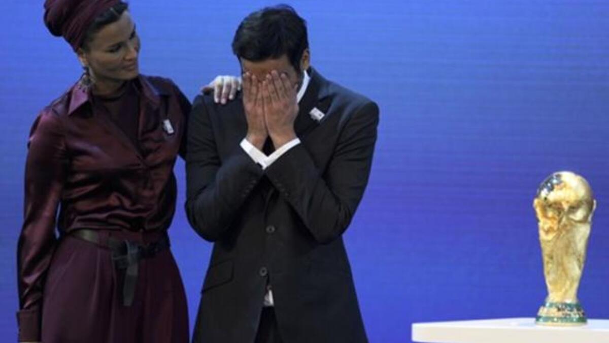 Chairman of Qatar 2022 Bid Committee Sheikh Mohammed bin Hamad Al-Thani (C) is comforted by Sheikha Moza bint Nasser Al-Missned on the podium with the World Cup trophy.