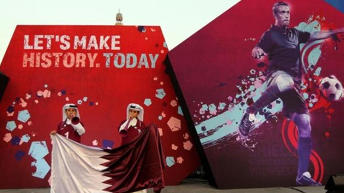 Qatari boys clad in traditional attire wave their national flag at Doha's traditional souk where people are gathering to follow FIFA's decision on who will host the 2022 World Cup.
