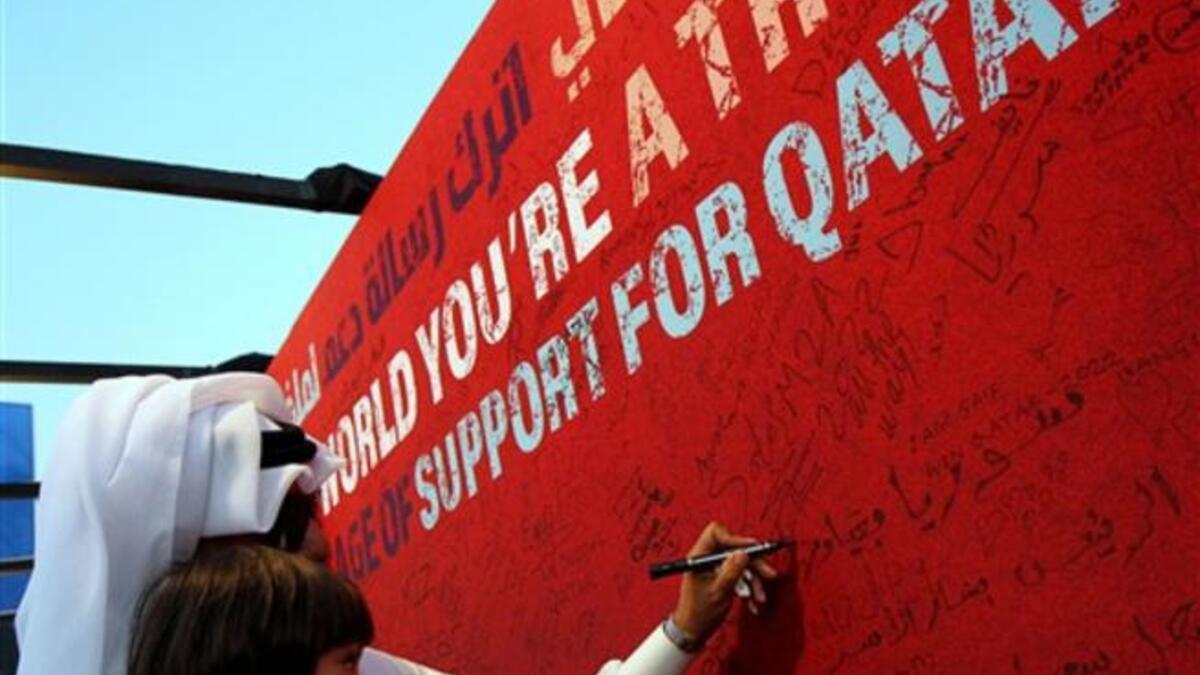 A Qatari man carrying his daughter writes a message on a board at Doha's traditional souk in support of his country's bid to host the 2022 World Cup before the tiny Gulf state was chosen by FIFA as a host.
