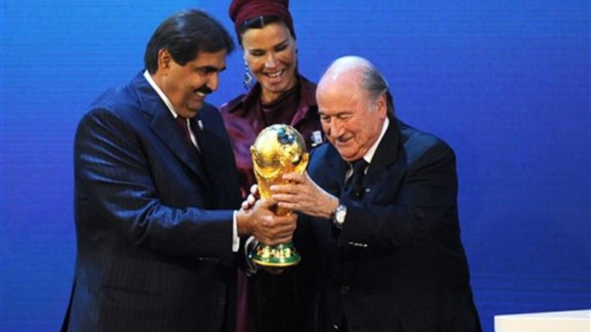 Fifa President Sepp Blatter (R) hands over the World Cup trophy to the Emir of the State of Qatar Sheikh Hamad bin Khalifa Al-Thani (L) and his wife.