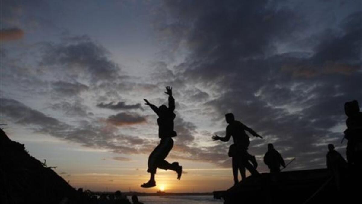 Palestinian boys jump from the top of a sand pile at the beach in Gaza City as they play outdoors during sunset, following storms and heavy rain that poured over the impoverished territory after months of drought.
