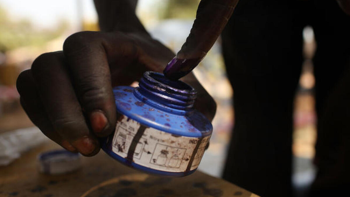 A woman places her finger in blue ink after voting.