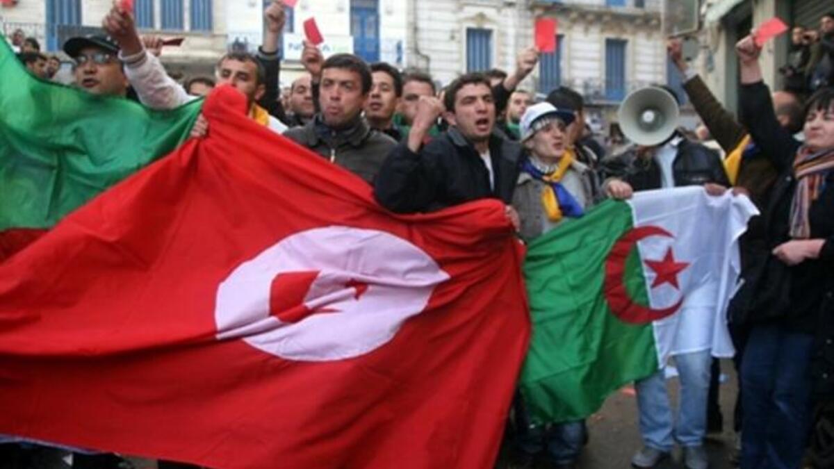 ALGERIA: Demonstrators wave flags outside the opposition Rally for Culture and Democracy party's headquarters in Algiers, January 22, 2011.