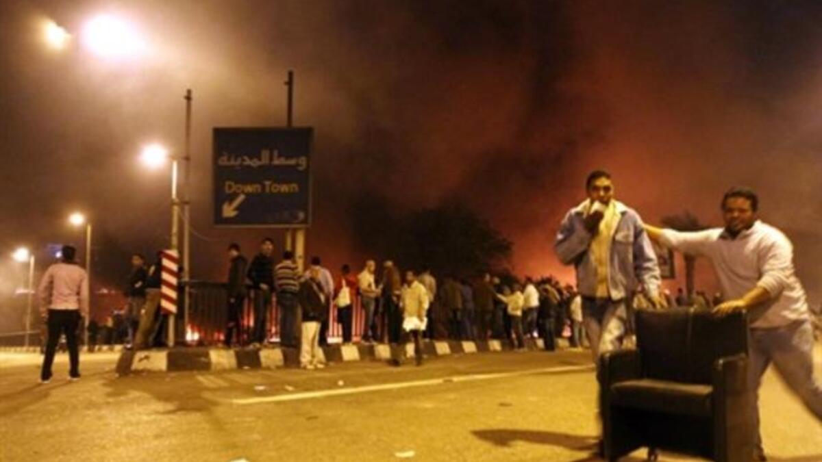 Looters roll a chair stolen from the burning headquarters of the of the ruling National Democratic party.