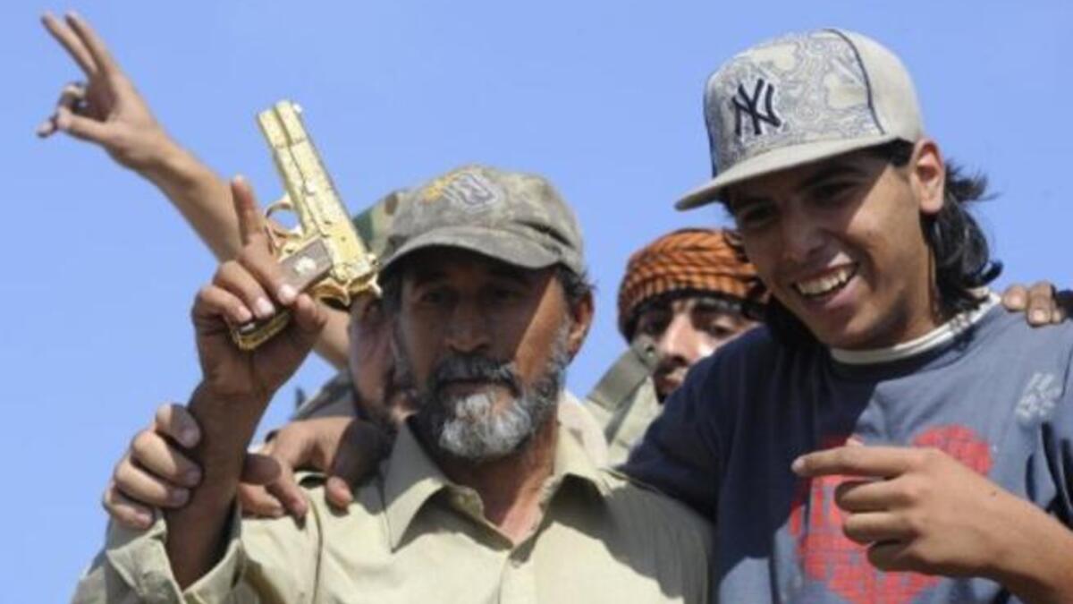 Jeering mobs have their moment. One man struck the former dictator with his shoe -- a grave insult in the Arab world. Shown here wielding what they claim to be the gold-plated gun of ousted Gaddafi at the site where the latterwas captured in the coastal Libyan city of Sirte. His golden gun hardly served the tattered man in his final moments.
