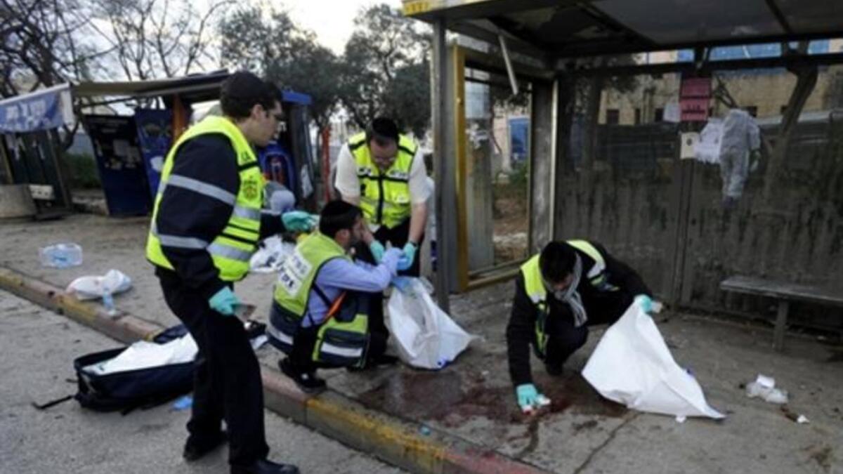 Israeli volunteers from the Zaka organization clean the blood stains and collect human remains at the scene of an explosion near Jerusalem's central bus station.