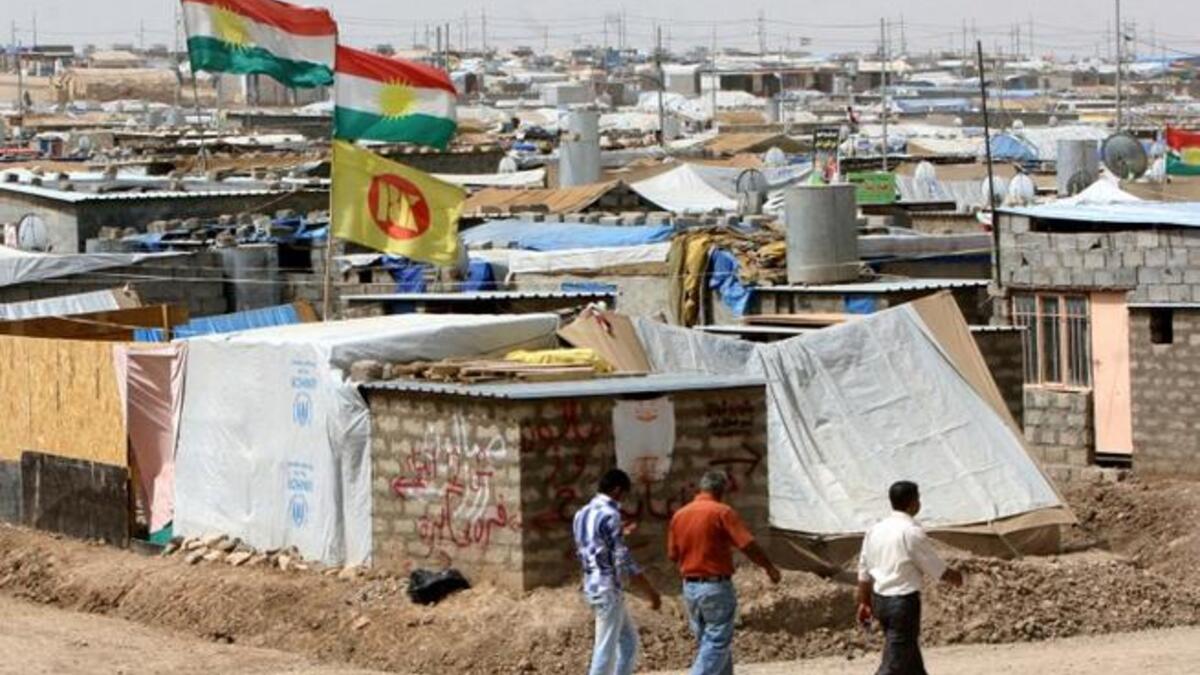 Syrian-Kurdish refugees walk along a dirt road at the Domiz refugee camp, 20 km southeast of the northern Iraqi city of Dohuk (AFP)