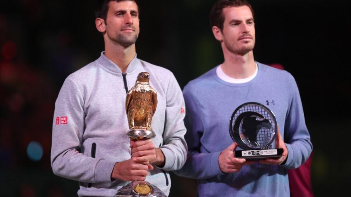 Serbia's Novak Djokovic (L) poses with the winner's trophy after beating Britain's Andy Murray during their final tennis match at the ATP Qatar Open in Doha on January 7, 2017.KARIM JAAFAR / AFP