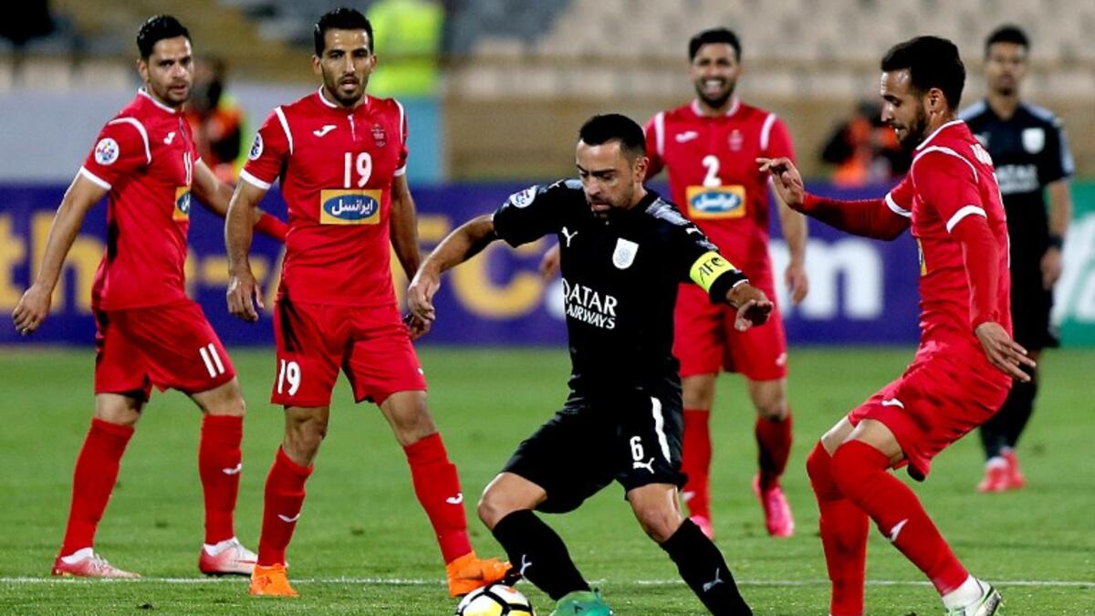 Al-Sadd's Xavier Hernandez (C) dribbles the ball as Persepolis' Ahmad Noorollahi (R) defends during the AFC Champions League match between al-Sadd and Persepolis at the Azadi Stadium in Tehran on April 16, 2018.
ATTA KENARE / AFP