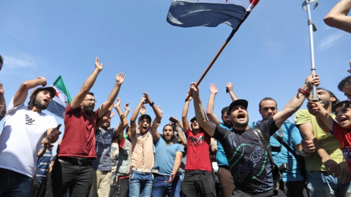 Syrian protesters wave the flag of the opposition as they demonstrate against the regime and its ally Russia, in the rebel-held city of Idlib on September 7, 2018.(OMAR HAJ KADOUR / AFP)