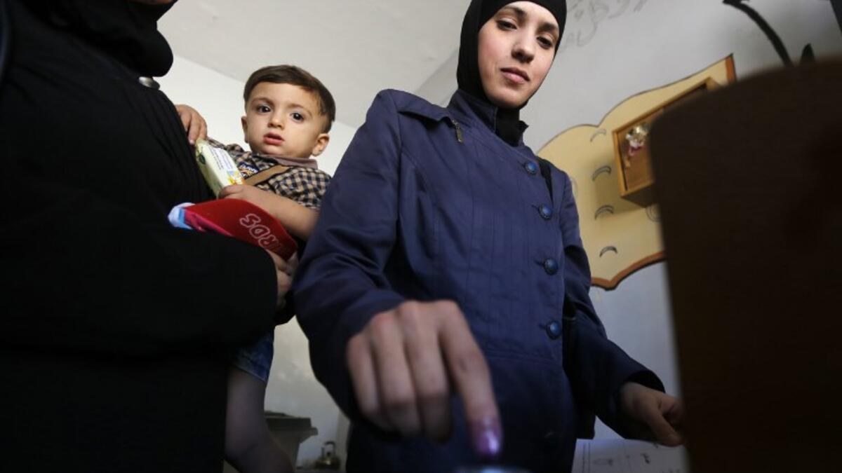 A woman dips her index finger in ink after casting her ballot for Syria's first local elections since 2011, on September 16, 2018. (LOUAI BESHARA / AFP)